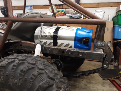 1985 Toyota Hilux - A close-up view of the rear suspension and frame of a custom off-road vehicle, possibly a modified Toyota Hilux. A large, knobby tire is vi…