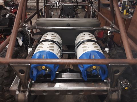 1985 Toyota Hilux - The rear interior of a custom-built vehicle shows two propane tanks mounted horizontally behind the seats. The vehicle has a roll cage and…