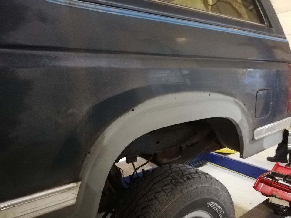 Dark blue SUV rear fender and wheel well, primer applied to fender flare