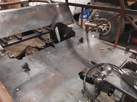 1985 Toyota Hilux - The bare metal chassis of a custom vehicle is shown, with parts of another vehicle in the background.
