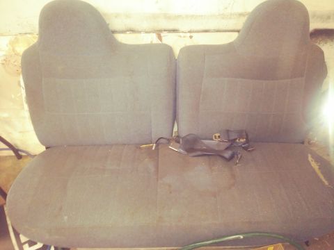 1996 Ford Bronco - The interior of a vehicle shows two adjacent seats with a seatbelt lying across them.