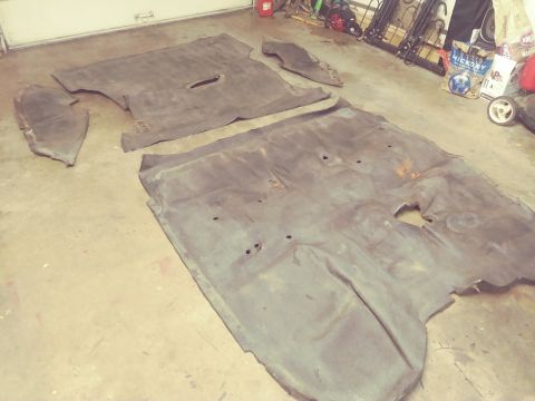 1996 Ford Bronco - Several pieces of car floor matting are spread out on a garage floor, appearing to be removed from a vehicle.