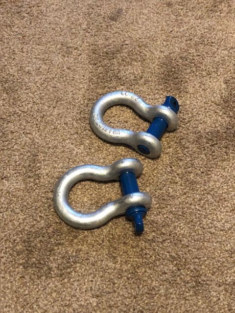 1981 Ford Bronco - Two silver tow shackles with blue pins are shown on a carpeted surface. The image includes a Supermotors.net watermark.