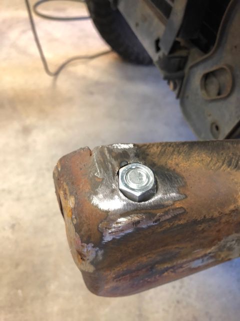 1981 Ford Bronco - Close-up of a rusty metal bracket with a newly installed bolt, indicating repair or modification.
