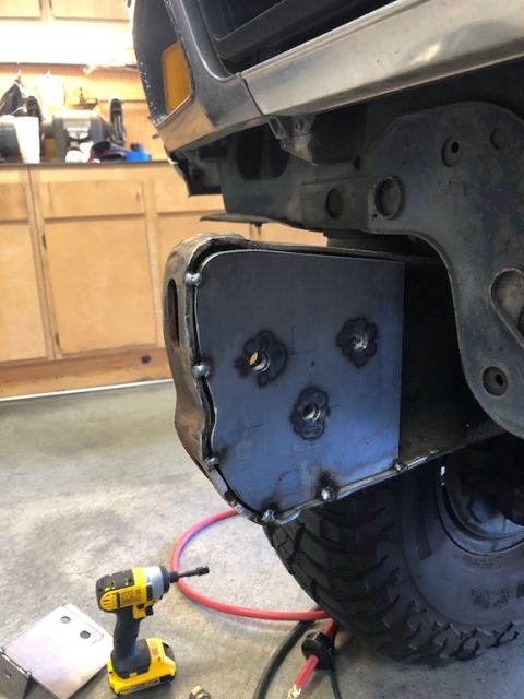 1981 Ford Bronco - Custom metal plates are being welded onto a vehicle's bumper assembly, with a drill visible nearby.