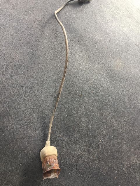 1979 Ford Bronco - A rusted electrical connector with a wire attached is shown against a gray, textured background.