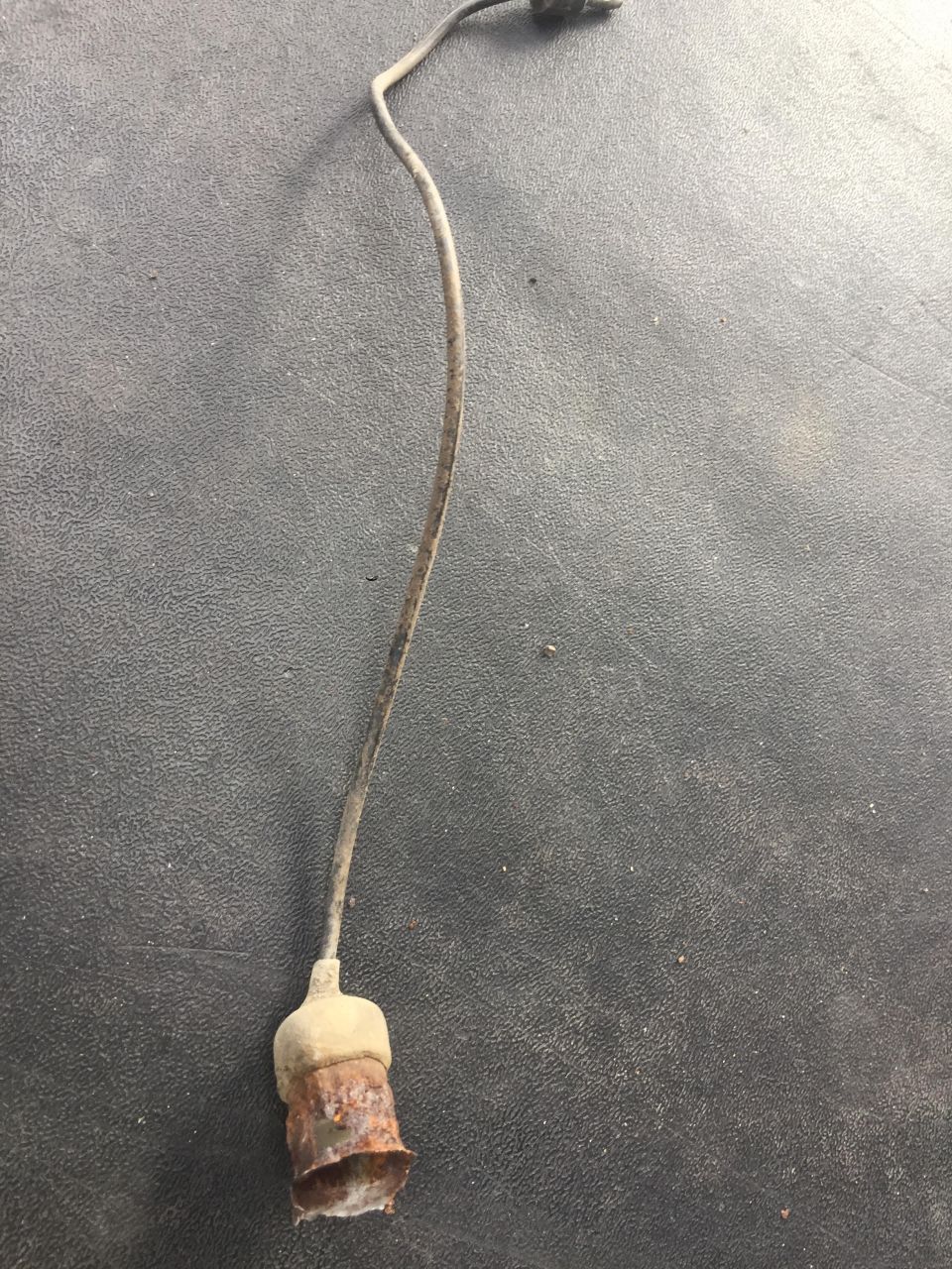 Rusted electrical connector and wire on gray surface