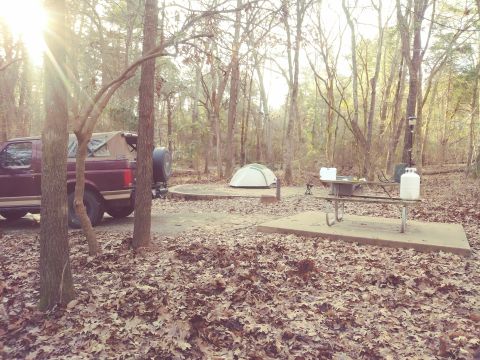 1996 Ford Bronco - A maroon 1996 Ford Bronco is parked at a campsite, ready for outdoor activities with a tent and picnic table nearby.