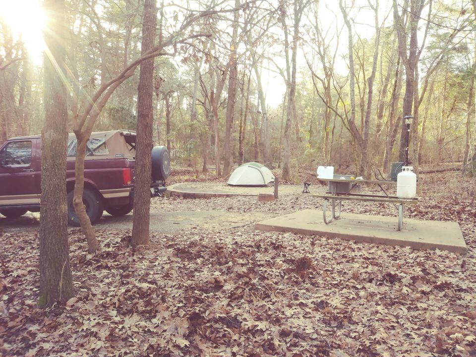 Maroon 1996 Ford Bronco parked at campsite with tent and picnic table