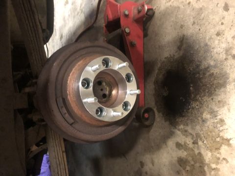 1979 Ford Bronco - A wheel spacer is attached to a vehicle's brake rotor, with a red jack visible.