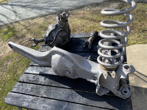 1994 Ford Bronco - Vehicle suspension parts are laid out on a weathered wooden surface, ready for installation or repair.