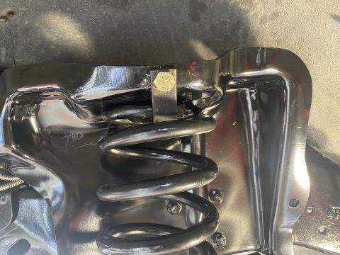 1994 Ford Bronco - A close-up view of a vehicle's suspension spring and its mounting bracket.