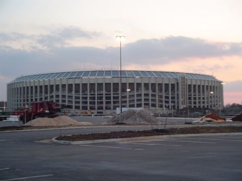 1979 Ford Bronco - Dusk view of a large round concrete stadium across an empty parking lot, with dirt piles and construction work in progress in the foregroun…