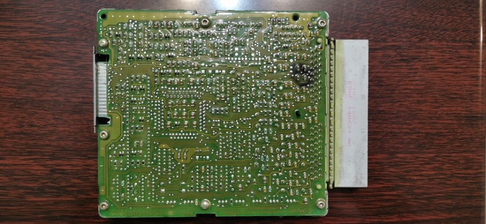 Electronic control unit circuit board with a white connector on a wooden surface. Text "SUPERMOTORS" is visible