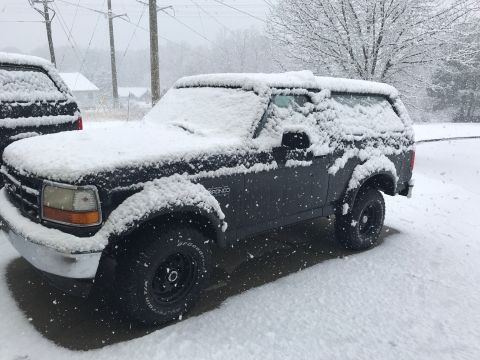 2008 Ford Focus - A Ford Bronco is parked outside during a snowstorm, with snow covering its body and the surrounding area.
