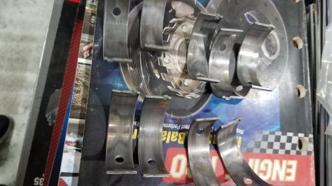 1985 Ford Bronco - Engine bearing parts are displayed on a surface text and a checkered flag pattern.