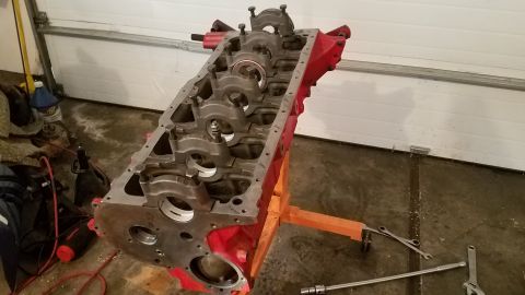 1985 Ford Bronco - Engine block on a stand, likely for repair or rebuilding, with tools scattered around the garage floor.