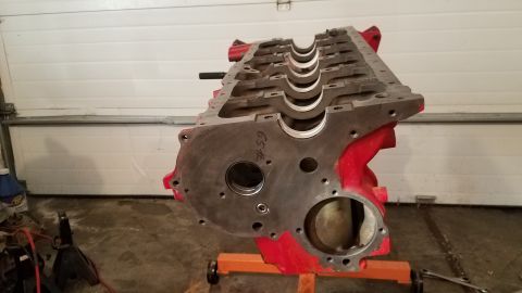 1985 Ford Bronco - A disassembled engine block sits on an orange stand in a garage, ready for repair or rebuilding.