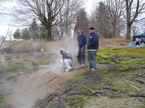 1979 Ford Bronco - A group of people are gathered in a misty outdoor environment, with one person examining the ground.
