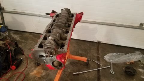 1985 Ford Bronco - An engine block is mounted on an engine stand in a garage, ready for repair or assembly.