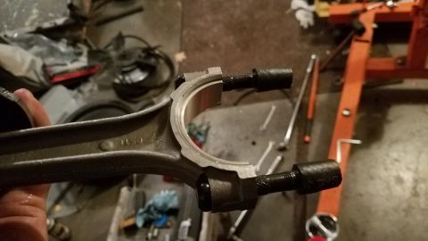 1985 Ford Bronco - Close-up of an engine connecting rod and bearing assembly in a garage setting.