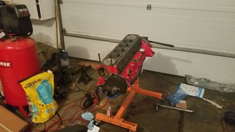 1985 Ford Bronco - Engine block assembly on a stand, likely for repair or rebuilding, with garage equipment in the background.