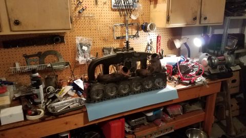 1985 Ford Bronco - Engine block on a workbench, surrounded by tools and automotive parts, suggesting a repair or rebuild process.