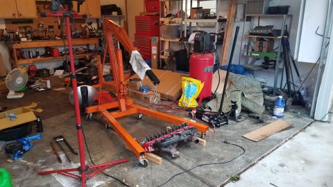 1985 Ford Bronco - Engine being worked on in a garage with an engine hoist and various tools.