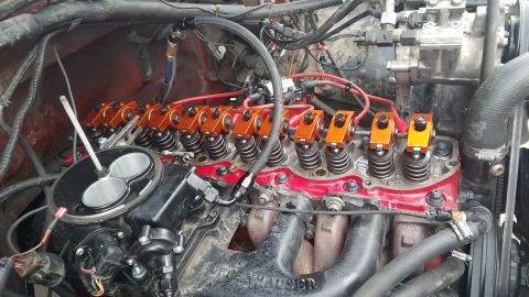 1985 Ford Bronco - Close-up view of the engine bay of a Ford Bronco, focusing on the intake manifold, throttle body, and orange roller rocker arms.