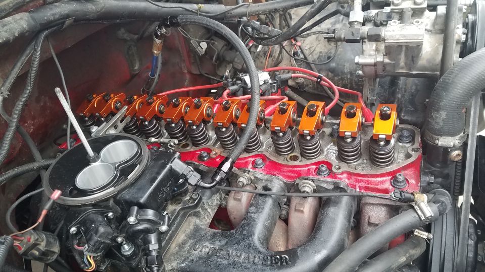 Close-up of a Ford Bronco engine bay with orange roller rocker arms and a throttle body.
