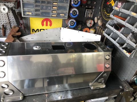1992 Jeep Wrangler - A custom-fabricated aluminum fuel tank sits on a workbench in a garage setting, surrounded by tools and automotive parts. The tank features…