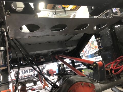1992 Jeep Wrangler - Underside view of a vehicle's chassis, showing suspension components, exhaust, and drivetrain parts. A metal plate with circular cutouts is…