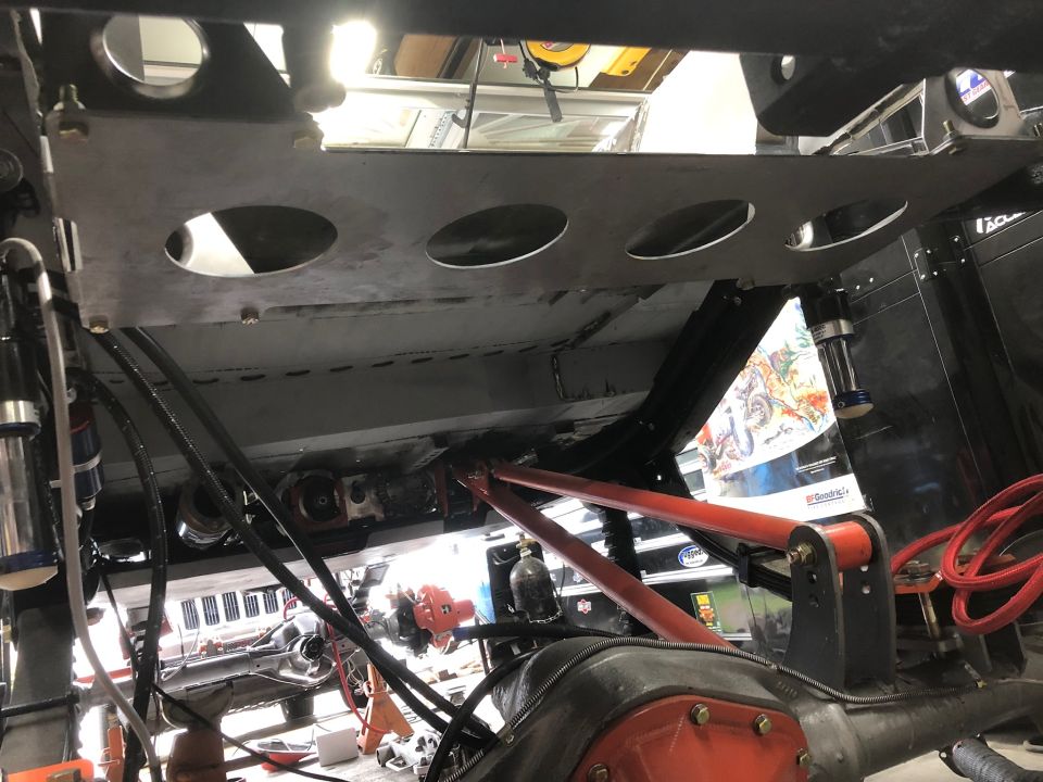 Underside of a vehicle chassis with suspension and drivetrain components visible.
