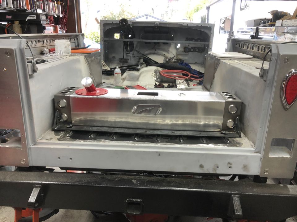 Polished aluminum fuel tank installed in the rear of a Jeep Wrangler.