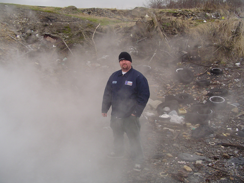 Man in a junkyard with steam and debris