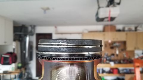 1985 Ford Bronco - A close-up, slightly angled view of the top of a piston with two visible rings and a wavy metal piece below them. The piston appears to be…