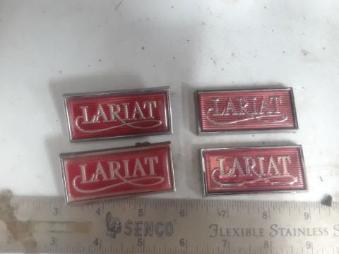 1994 Ford Bronco - Two pairs of red and silver "Lariat" emblems are displayed on a white surface next to a ruler. The emblems appear to be for a vehicle part.