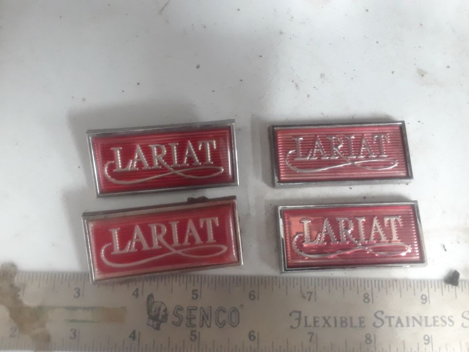 Two pairs of red and silver "Lariat" emblems on a white surface.