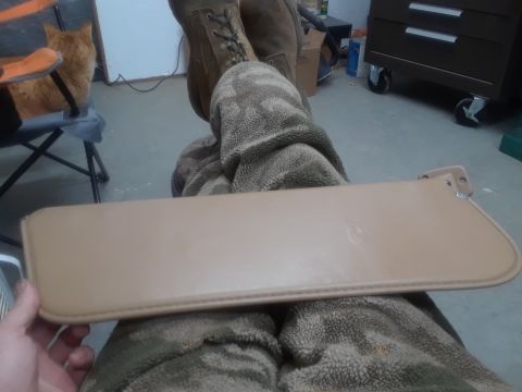 1994 Ford Bronco - A tan-colored sun visor is held in front of a person wearing camouflage pants and boots. The visor appears to be for a vehicle.
