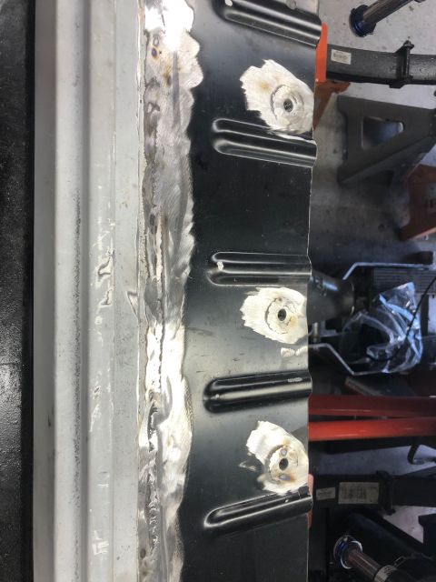 1992 Jeep Wrangler - Close-up of a vehicle's metal body panel showing welding repairs and threaded mounting points. The panel is a dark color with areas of silv…