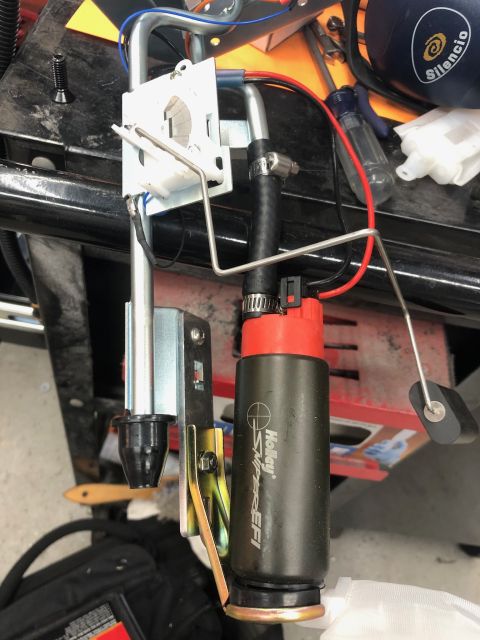 1992 Jeep Wrangler - A close-up view of a Holley Sniper EFI fuel pump assembly with a float mechanism and wiring. The fuel pump is black with a red top and has…