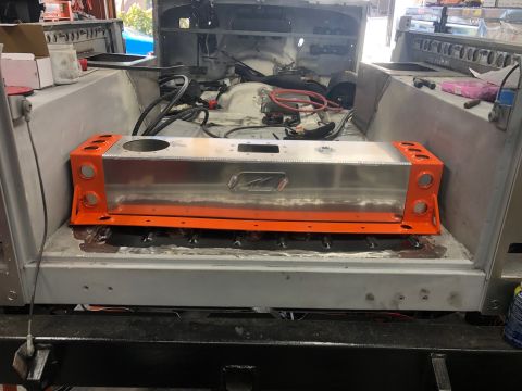 1992 Jeep Wrangler - The rear interior of a vehicle build is shown, featuring a large, silver, rectangular fuel tank with orange metal brackets on each end. The…