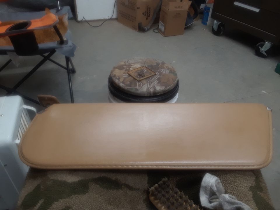 Tan sun visor on a camouflage rug with a brush and cloth.