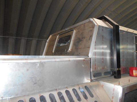 1992 Ford Bronco - A custom aluminum body is being constructed on a vehicle chassis inside a building with a corrugated metal roof. The structure has a window…
