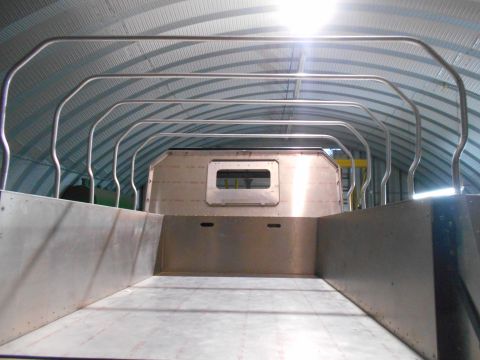 1992 Ford Bronco - Interior view of a custom-built aluminum truck bed with a roll cage structure overhead. The vehicle is inside a large, corrugated metal bui…