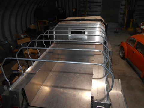 1992 Ford Bronco - An elevated view of a custom-built aluminum structure with railings, possibly a vehicle modification or a custom trailer, parked inside a w…