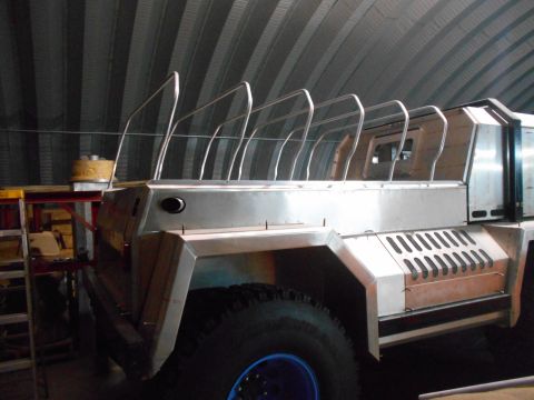 1992 Ford Bronco - A custom-built, unfinished vehicle with a brushed metal body and roll cage structure is parked inside a metal building. The vehicle feature…