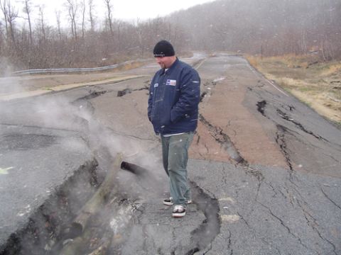 1979 Ford Bronco - A man surveys a road severely damaged by a landslide, with steam emanating from a deep fissure.