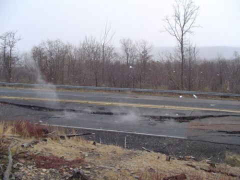 1979 Ford Bronco - A damaged road shows significant cracking and steam rising from the surface, indicating a potential subsurface issue.