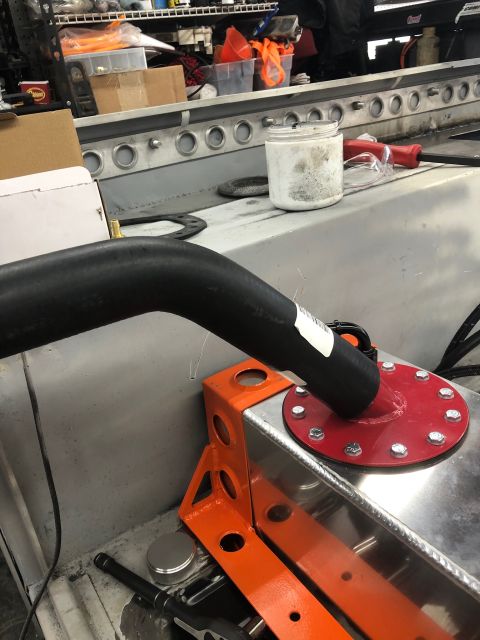1992 Jeep Wrangler - A close-up view shows a black hose connected to a red fuel cell cap on a silver fuel tank. The fuel tank is mounted with an orange bracket.